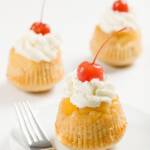 pineapple upside-down cupcakes topped with whipped cream and maraschino cherries