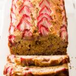 A loaf of strawberry banana bread with three slices falling down from it