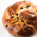 Round challah loaf with raisins on a white countertop