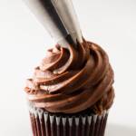Chocolate cream cheese frosting being piped onto a chocolate cupcake