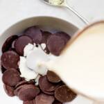 Hot cream being poured over dark chocolate discs