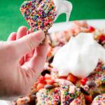 Funfetti Dessert Nachos being held up over a bowl of dessert nachos