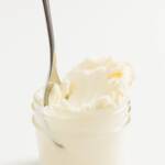 A jar of clotted cream with a spoon resting inside