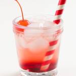 A glass with a Shirley Temple non-alcoholic cocktail, Maraschino cherry, and straw
