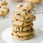 Stack of cookies on a white plate with a cooling rack of cookies in the background