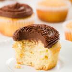 tight shot of an interior of a pound cake cupcake frosted with chocolate ganache frosting with other cupcakes in the background