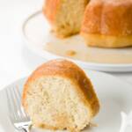 tight shot of a slice of rum cake on a plate with the remainder of the cake in the background