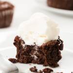 Flourless chocolate cupcake cut open on a plate with a dripping scoop of ice cream on top