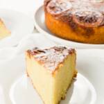 slice of lemon olive oil cake on a plate with the cake in the background