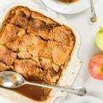 Overhead shot of pan of apple pandowdy, plates with food, and apples