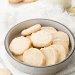 Lavender shortbread in a grey bowl with cookies and milk around it