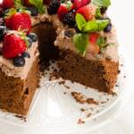 Chocolate angel food cake on a white cake stand with several slices reomoved